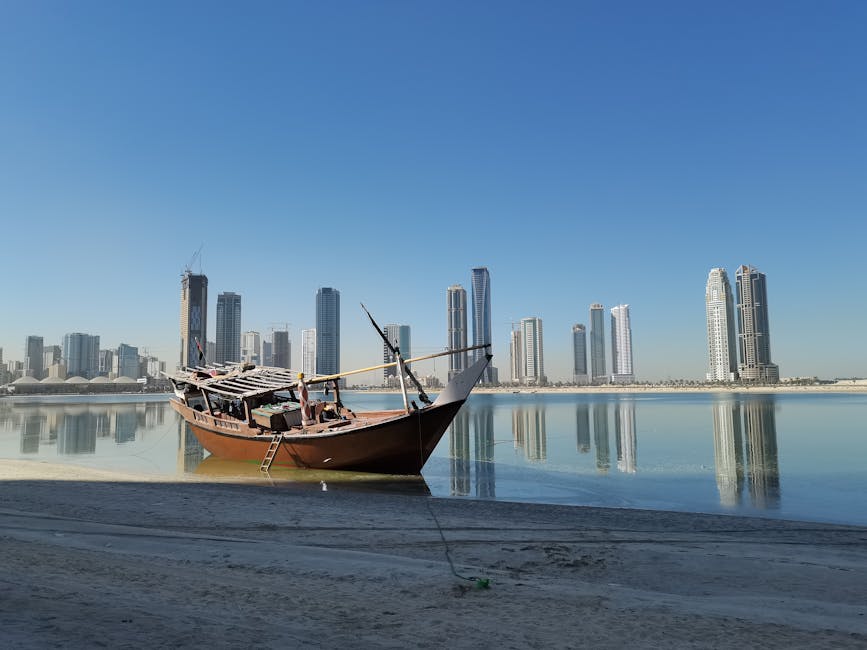 A dhow boat by the Sharjah skyline reflecting in the calm water.