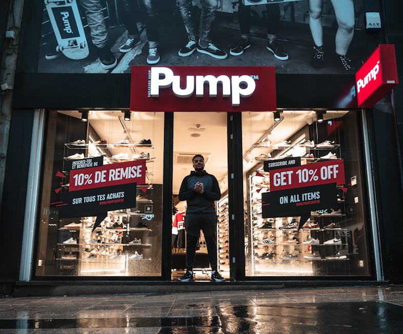 Illuminated shoe store Pump in Brussels with sale signs and reflections at night.